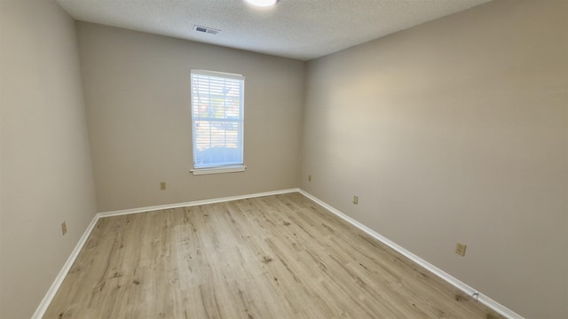 unfurnished room featuring a textured ceiling and light hardwood / wood-style flooring