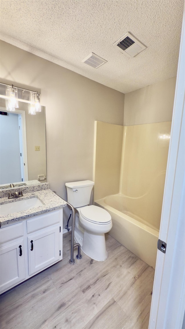 full bathroom featuring hardwood / wood-style floors, toilet, vanity, and a textured ceiling