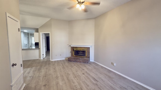 unfurnished living room with light wood-type flooring, ceiling fan, and a brick fireplace