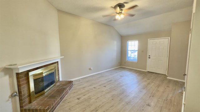 unfurnished living room with vaulted ceiling, ceiling fan, light hardwood / wood-style floors, and a fireplace