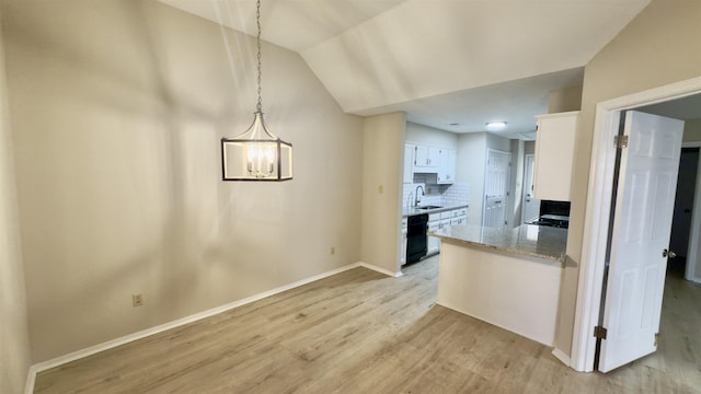 kitchen with white cabinets, lofted ceiling, decorative light fixtures, black dishwasher, and tasteful backsplash