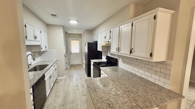 kitchen with backsplash, black appliances, sink, white cabinetry, and light stone counters