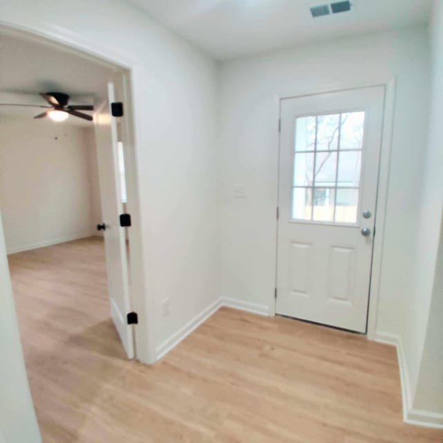 doorway with ceiling fan and light hardwood / wood-style flooring