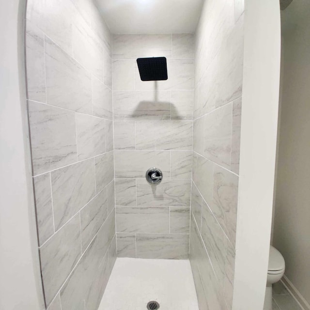 bathroom with toilet and a tile shower