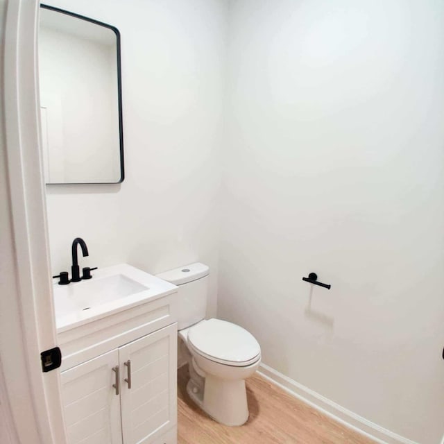 bathroom featuring toilet, hardwood / wood-style flooring, and vanity