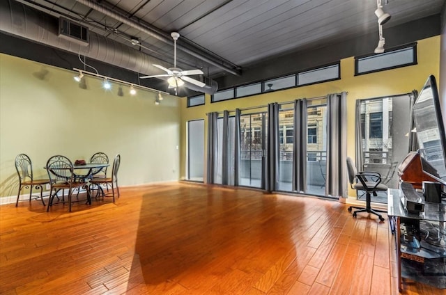 interior space featuring a high ceiling, hardwood / wood-style flooring, track lighting, and ceiling fan