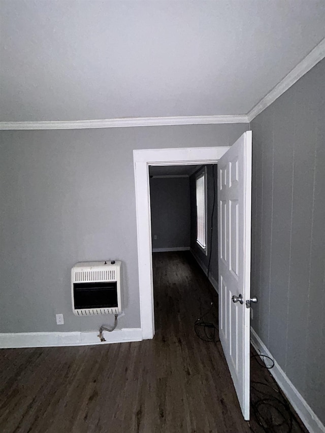 empty room featuring crown molding, dark hardwood / wood-style flooring, and heating unit