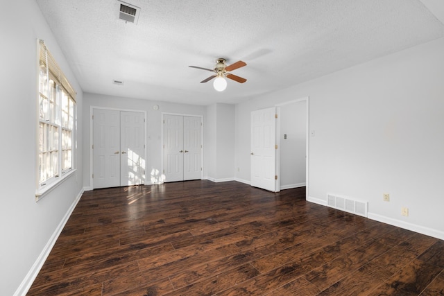 unfurnished room with a textured ceiling, ceiling fan, and dark hardwood / wood-style floors