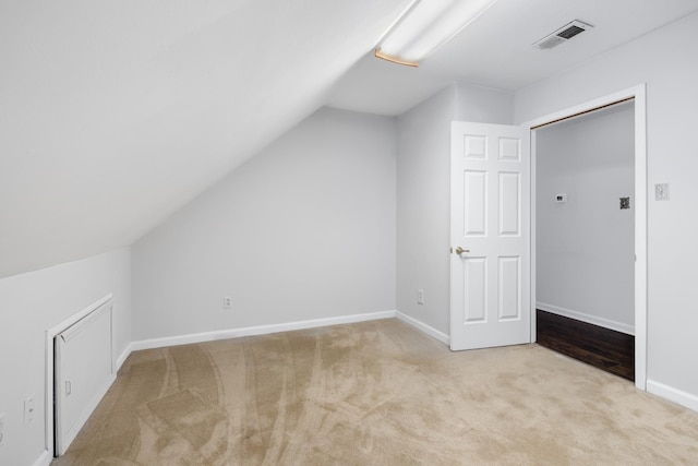 additional living space featuring vaulted ceiling and light colored carpet