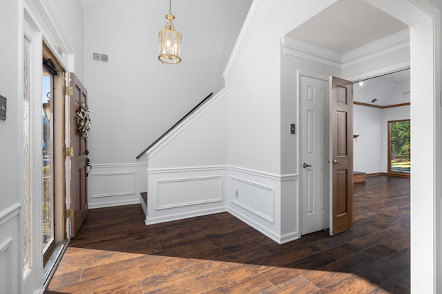 foyer entrance with a chandelier, crown molding, and dark hardwood / wood-style flooring