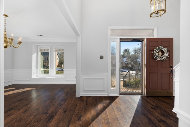 foyer featuring dark wood-type flooring, an inviting chandelier, and a wealth of natural light