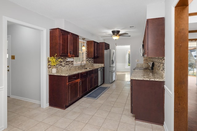 kitchen with sink, decorative backsplash, light stone counters, and appliances with stainless steel finishes