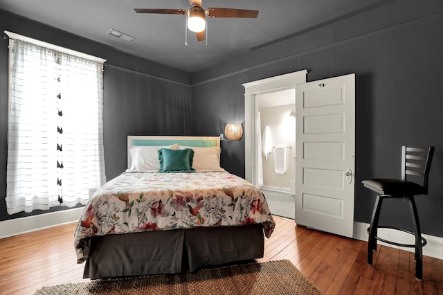 bedroom with connected bathroom, hardwood / wood-style floors, and ceiling fan