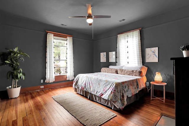 bedroom with hardwood / wood-style floors, ceiling fan, and multiple windows