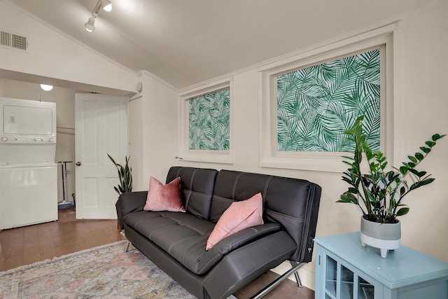 living room featuring stacked washing maching and dryer, hardwood / wood-style floors, and vaulted ceiling