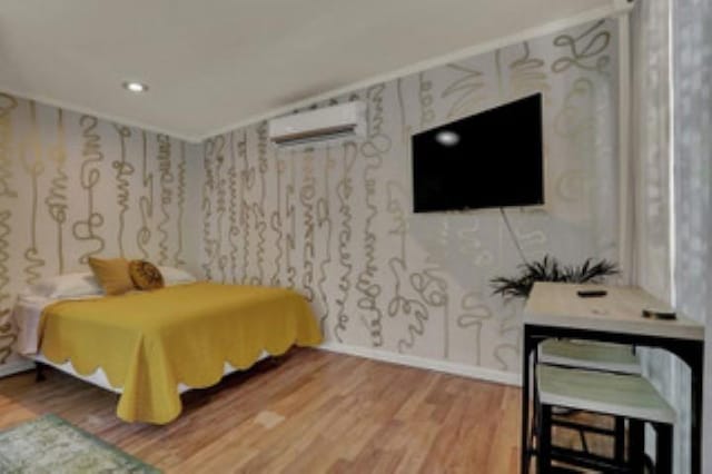 bedroom featuring wood-type flooring and an AC wall unit