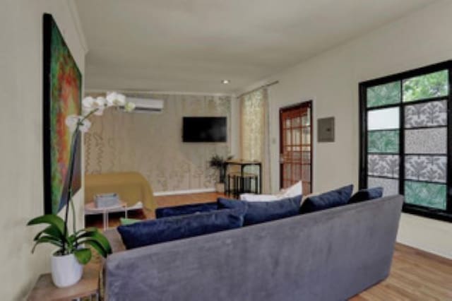 living room with hardwood / wood-style flooring and a wall mounted air conditioner