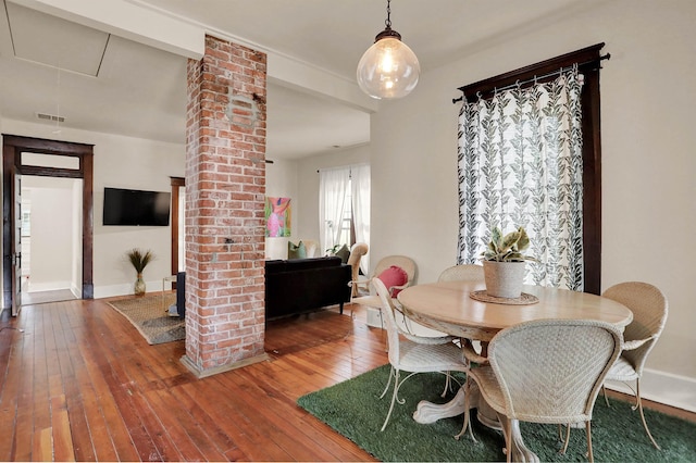 dining area with hardwood / wood-style floors and ornate columns