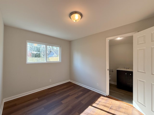 unfurnished bedroom with sink, connected bathroom, and dark wood-type flooring