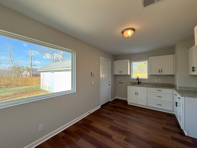 kitchen featuring sink, white cabinets, dark wood-type flooring, and light stone countertops