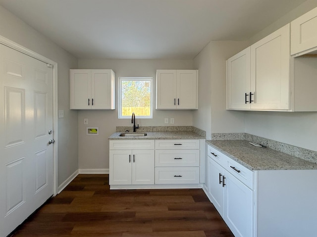 kitchen with sink, white cabinets, dark hardwood / wood-style floors, and light stone countertops