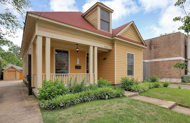 view of front facade with a garage, a porch, an outbuilding, and a front lawn