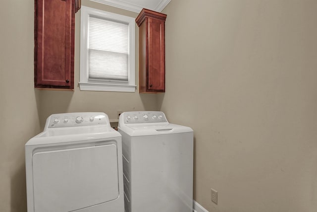 washroom with cabinets, washing machine and dryer, and crown molding