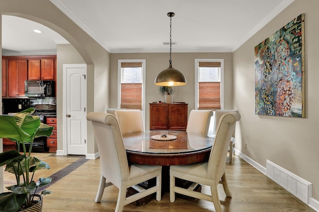 dining room with light wood-type flooring, a healthy amount of sunlight, and crown molding