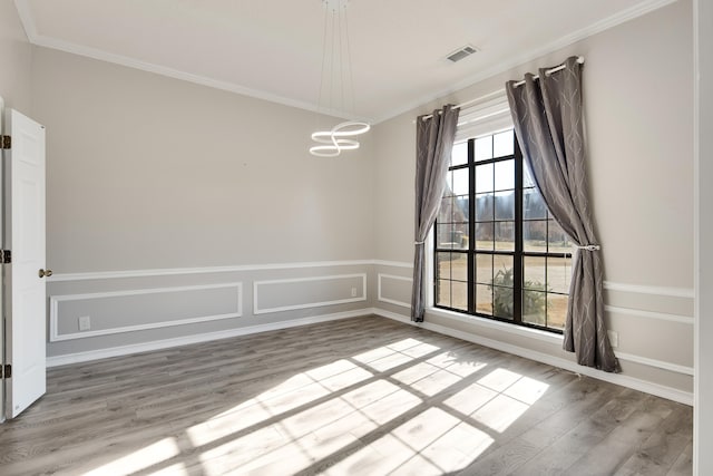 unfurnished room with ornamental molding, light wood-type flooring, and a notable chandelier