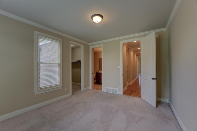 unfurnished bedroom with a spacious closet, light carpet, a closet, and crown molding