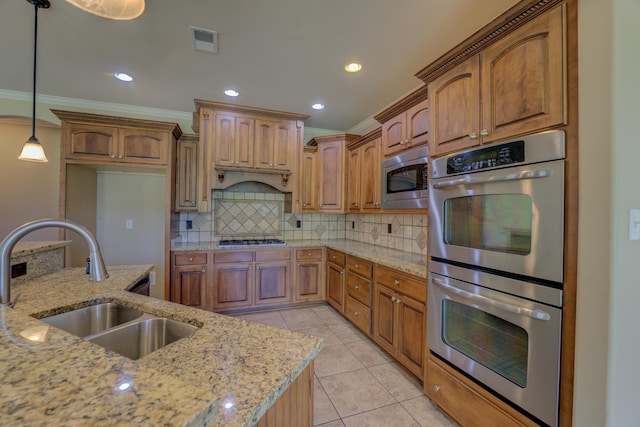 kitchen featuring light stone countertops, decorative light fixtures, tasteful backsplash, appliances with stainless steel finishes, and sink