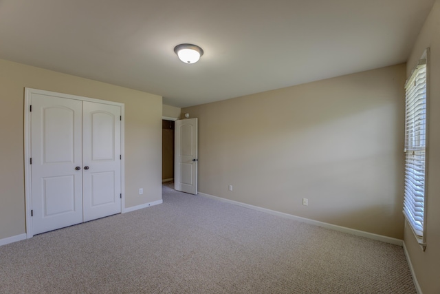 unfurnished bedroom with light colored carpet, a closet, and multiple windows