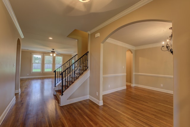 interior space featuring ceiling fan with notable chandelier, ornamental molding, and dark hardwood / wood-style floors