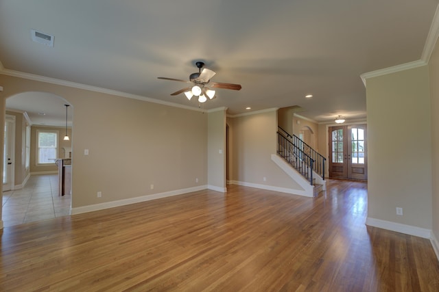 unfurnished living room featuring light wood-type flooring, french doors, ceiling fan, and crown molding