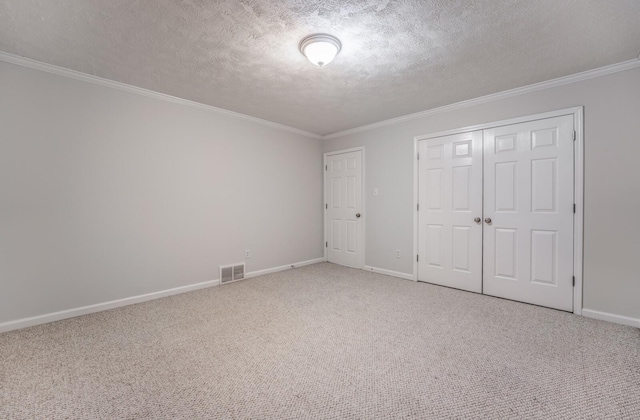 unfurnished bedroom featuring a closet, ornamental molding, a textured ceiling, and carpet floors