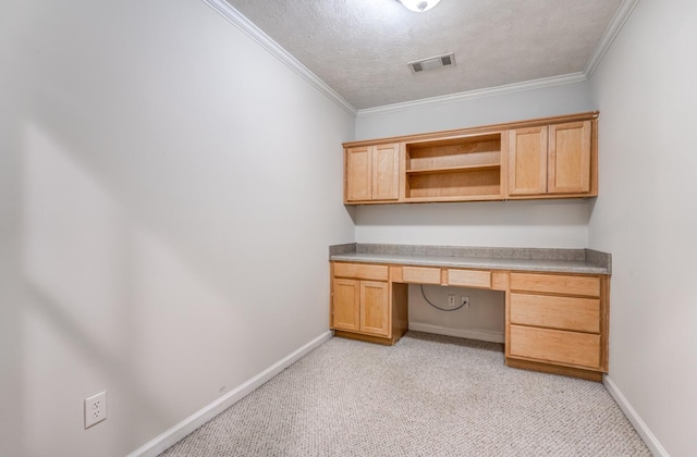 unfurnished office with built in desk, a textured ceiling, light carpet, and crown molding