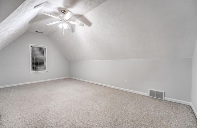 additional living space featuring lofted ceiling, a textured ceiling, ceiling fan, and carpet