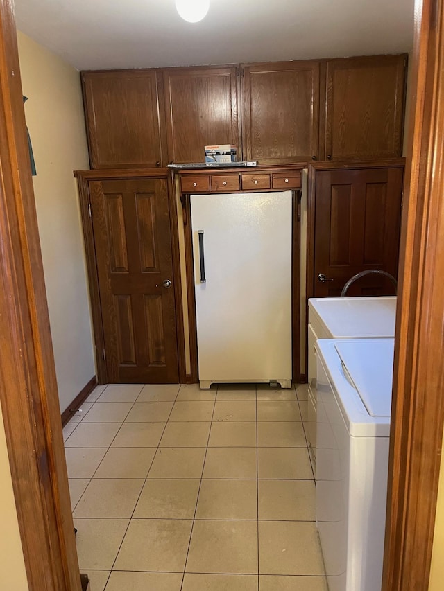 clothes washing area with independent washer and dryer, cabinets, and light tile patterned floors