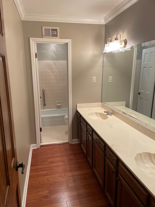 full bathroom with tiled shower / bath, hardwood / wood-style flooring, toilet, vanity, and crown molding