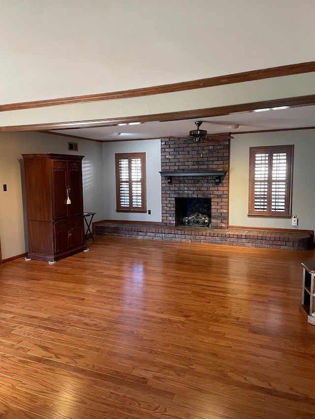 unfurnished living room with hardwood / wood-style flooring, a brick fireplace, and plenty of natural light