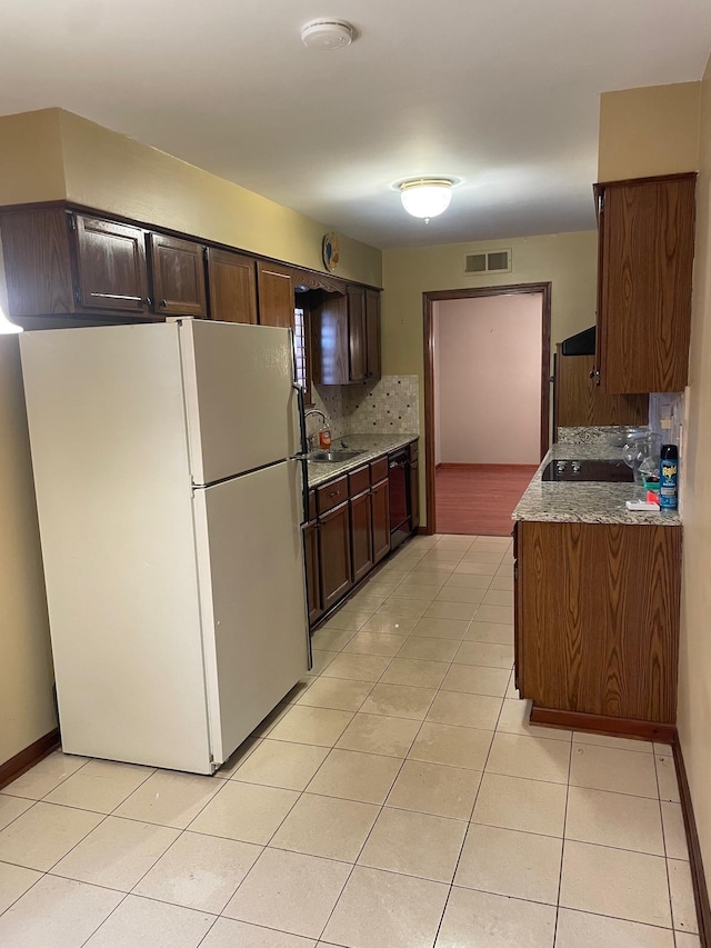 kitchen featuring backsplash, light tile patterned floors, black appliances, and dark brown cabinets