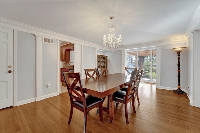 dining area with a notable chandelier, crown molding, and wood-type flooring