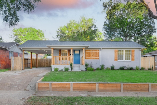 view of front of home with a porch, a yard, and a carport