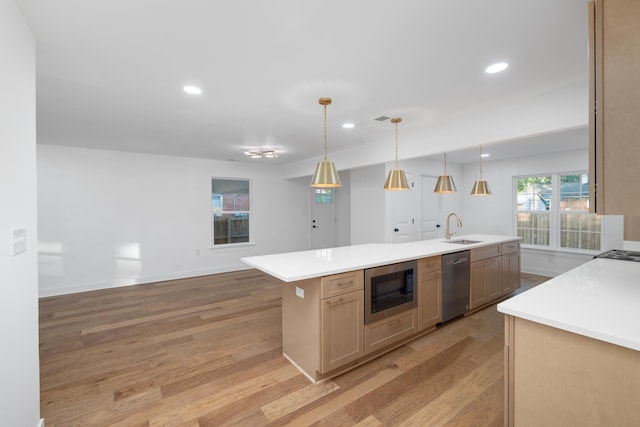 kitchen with a kitchen island with sink, built in microwave, sink, light hardwood / wood-style flooring, and stainless steel dishwasher