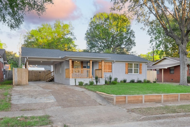 ranch-style home featuring a porch, a yard, and a carport