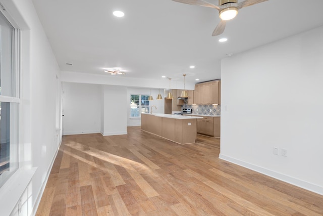 unfurnished living room with light wood-type flooring, ceiling fan, and sink