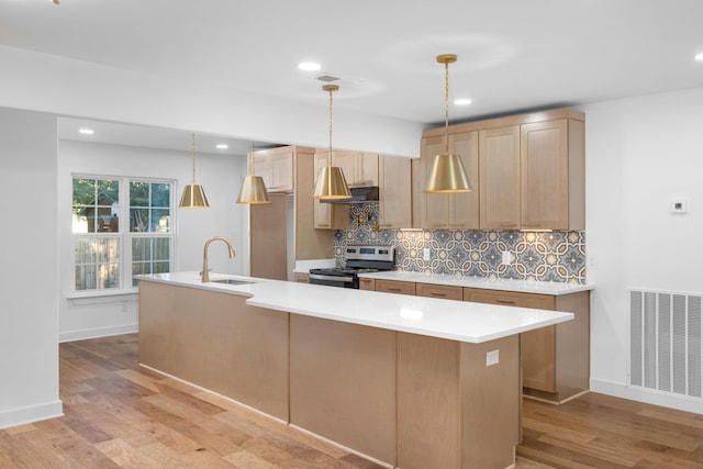 kitchen with stainless steel electric stove, backsplash, sink, and pendant lighting