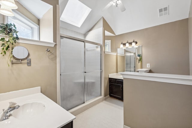 bathroom featuring a shower with door, vanity, lofted ceiling with skylight, and ceiling fan