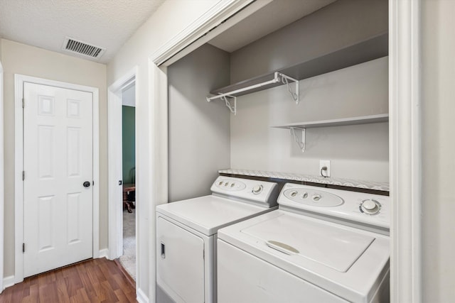 laundry area featuring dark wood-type flooring, a textured ceiling, and separate washer and dryer