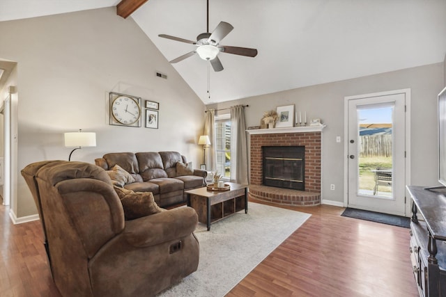 living room with ceiling fan, vaulted ceiling with beams, a fireplace, and wood-type flooring